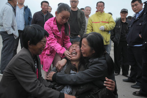 Relatives wait for news of missing family members outside the premises of Jilin Baoyuanfeng Poultry Co.  Families cling to fading hopes of finding survivors