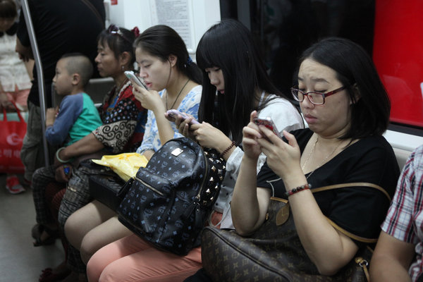 People scan their cellphones in a subway train in Beijing, August 30, 2013.  When smartphones attack