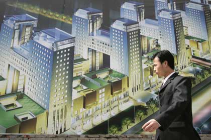 A man walks past a billboard for a new property development being erected in Beijing April 24, 2006.
