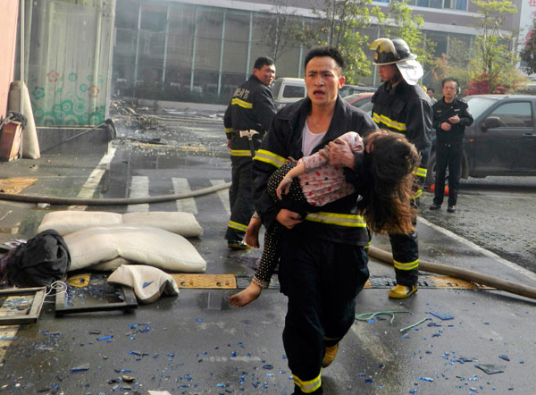 A firefighter rushes a girl out of a fire that killed at least 14 people in Xiangyang, Central China's Hubei province, April 14, 2013.  Death toll rises to 14 in central China hotel fire