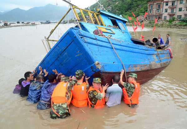 Troops and fishermen try to move a boat to a safer spot in Xiapu, Fujian province, on Thursday, after it was overturned by the powerful winds of Typhoon Trami. Yuan Ziyou for China Daily  Trami batters southern China